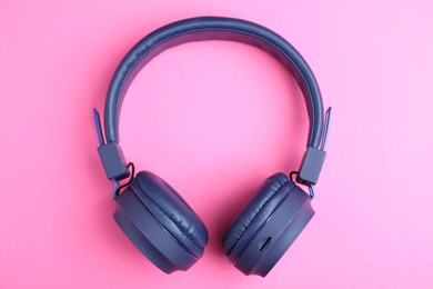 Photo of Pair of stylish blue headphones on pink background, top view