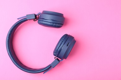 Photo of Pair of stylish blue headphones on pink background, top view. Space for text