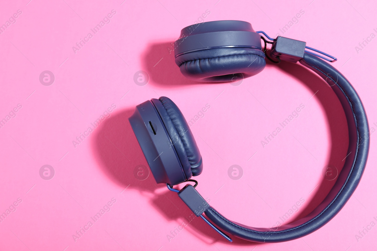 Pair of stylish blue headphones on pink background, top view. Space for text Photo of Pair of stylish blue headphones on pink background, top view. Space for text