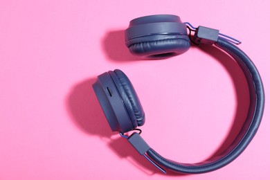 Photo of Pair of stylish blue headphones on pink background, top view. Space for text