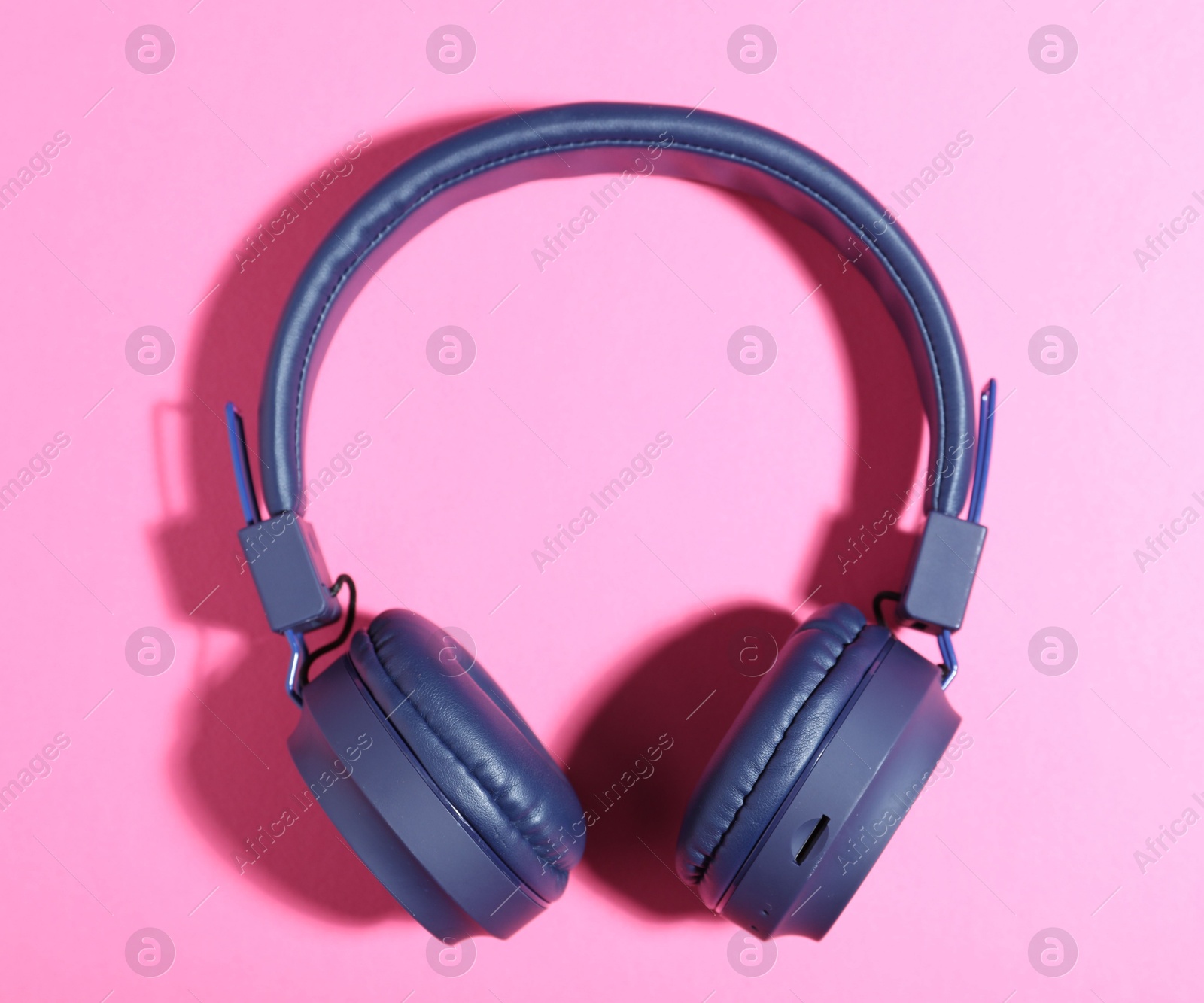Pair of stylish blue headphones on pink background, top view Photo of Pair of stylish blue headphones on pink background, top view