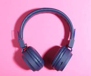 Photo of Pair of stylish blue headphones on pink background, top view