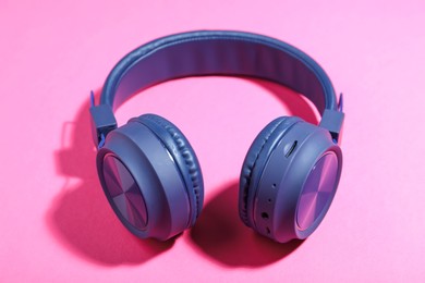 Photo of Pair of stylish blue headphones on pink background, closeup