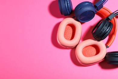 Photo of Different stylish headphones on pink background, flat lay. Space for text