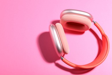 Photo of Pair of stylish headphones on pink background, top view. Space for text