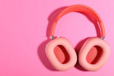 Photo of Pair of stylish headphones on pink background, top view. Space for text