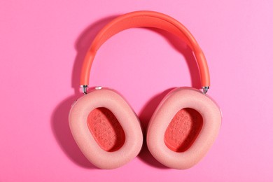 Photo of Pair of stylish headphones on pink background, top view