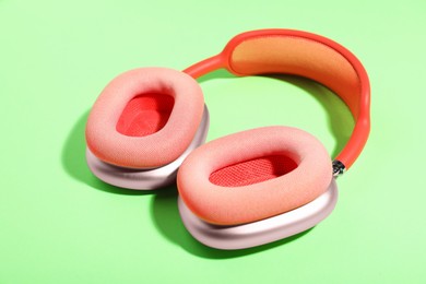Photo of Pair of stylish pink headphones on light green background