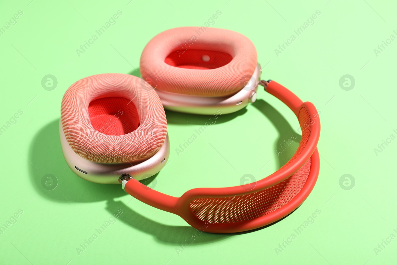 Pair of stylish pink headphones on light green background Photo of Pair of stylish pink headphones on light green background