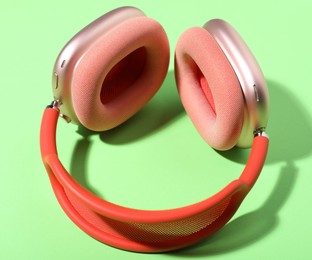 Photo of Pair of stylish pink headphones on light green background