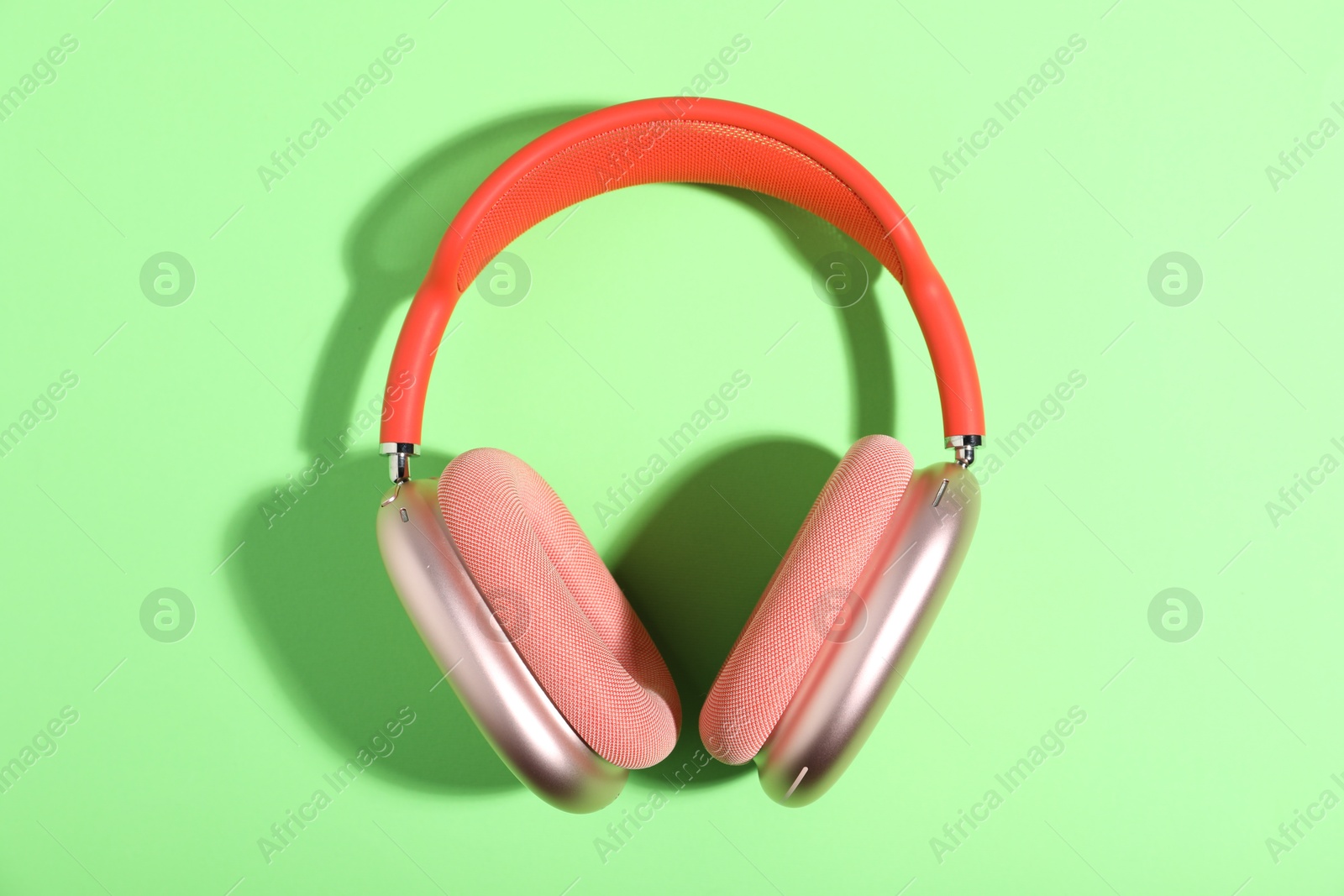 Pair of stylish pink headphones on light green background, top view Photo of Pair of stylish pink headphones on light green background, top view