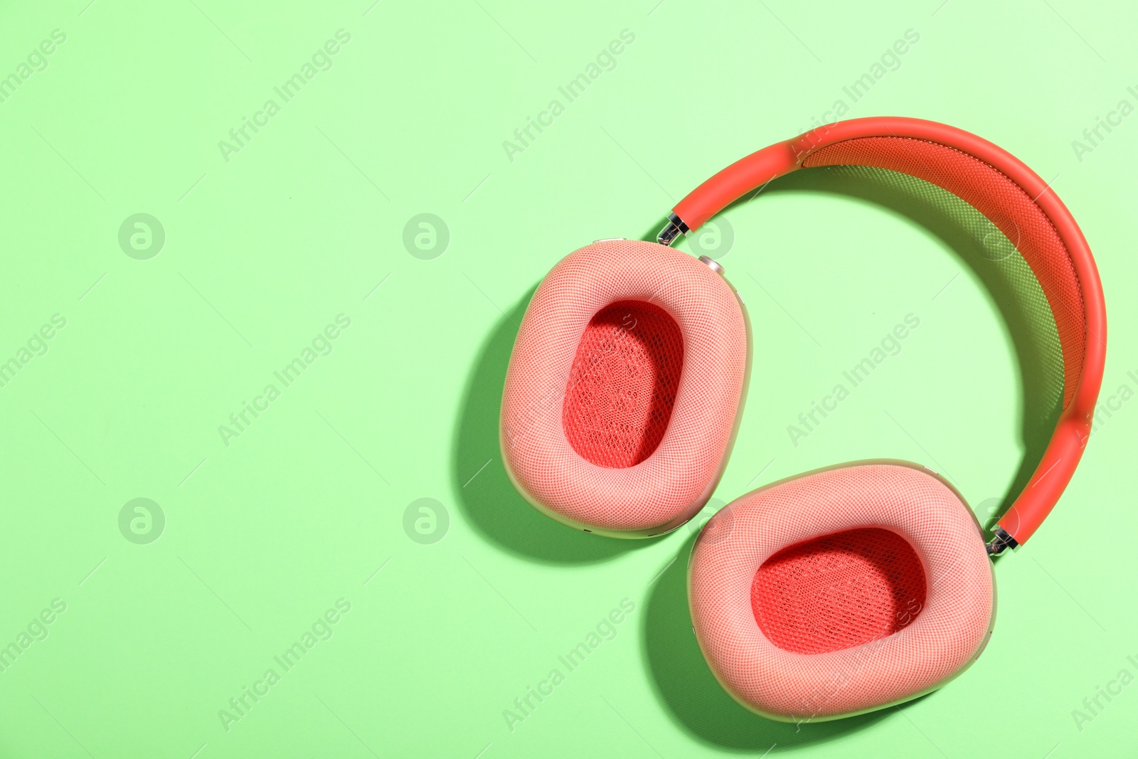 Pair of stylish pink headphones on light green background, top view. Space for text Photo of Pair of stylish pink headphones on light green background, top view. Space for text