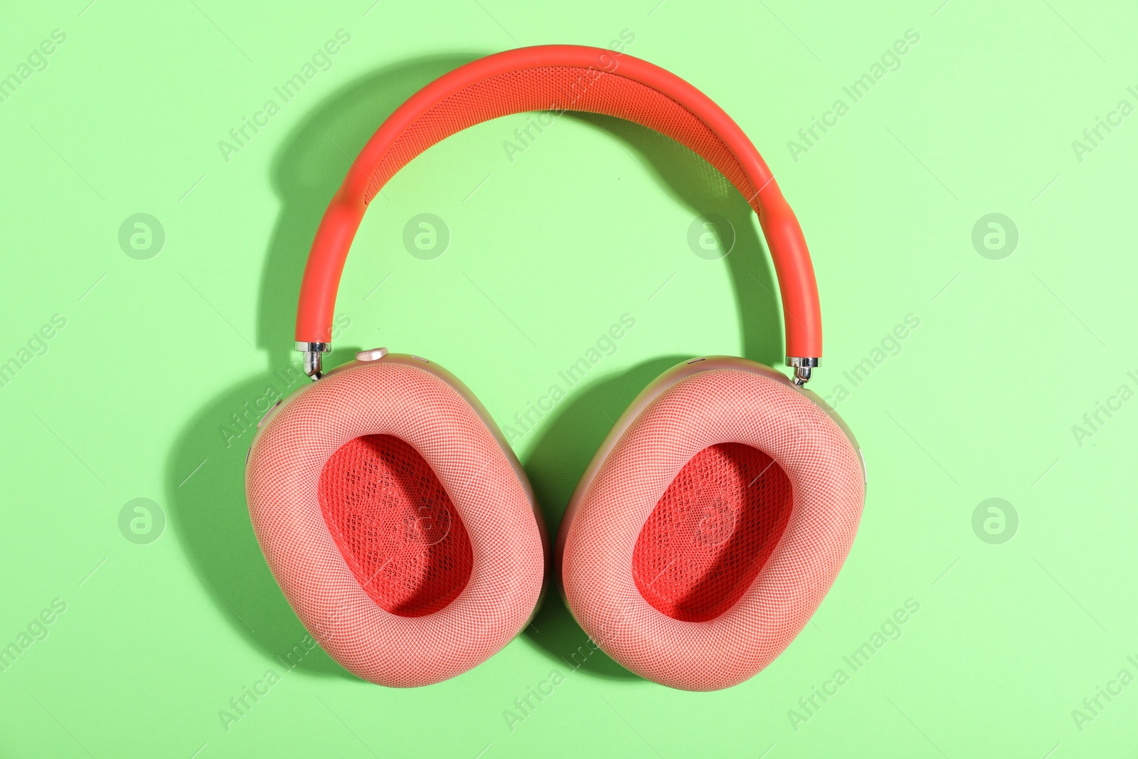 Pair of stylish pink headphones on light green background, top view Photo of Pair of stylish pink headphones on light green background, top view