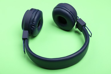 Photo of Pair of stylish blue headphones on light green background