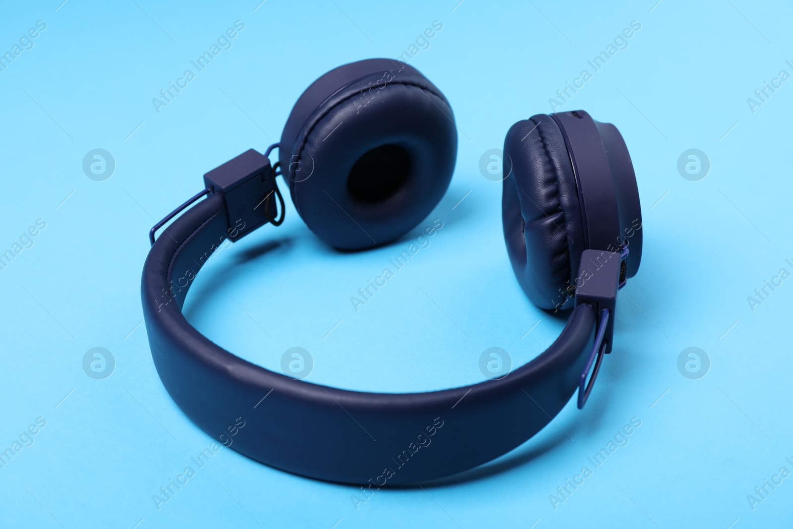 Pair of stylish headphones on light blue background Photo of Pair of stylish headphones on light blue background