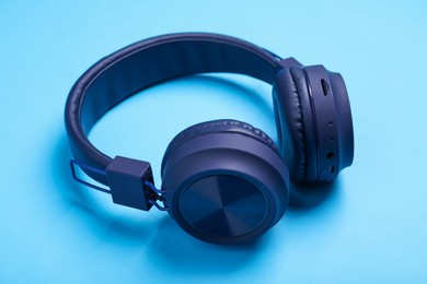 Photo of Pair of stylish headphones on light blue background, closeup