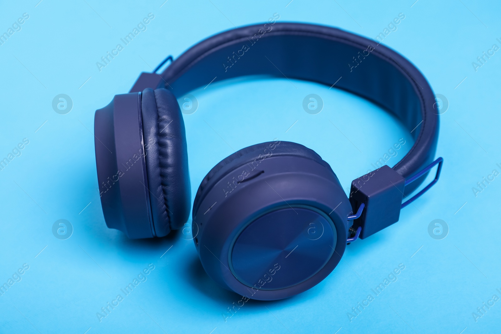 Pair of stylish headphones on light blue background, closeup Photo of Pair of stylish headphones on light blue background, closeup