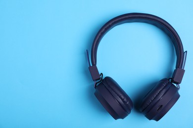 Photo of Pair of stylish headphones on light blue background, top view. Space for text