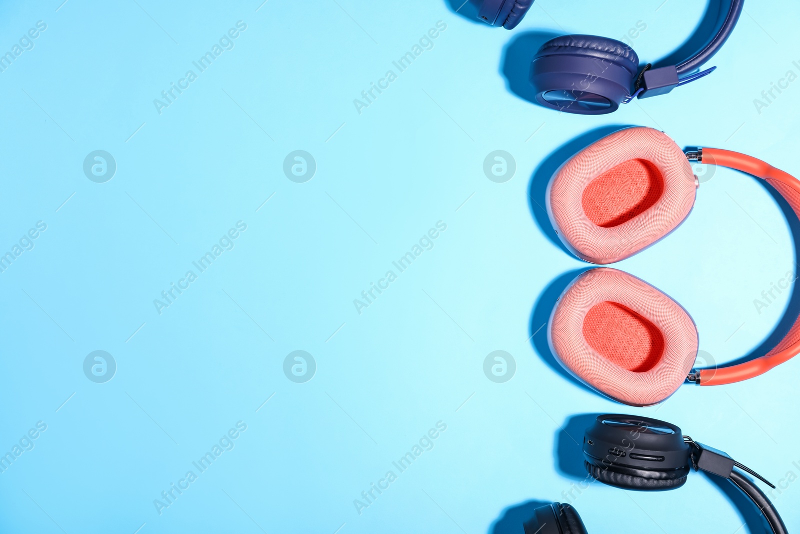 Different stylish headphones on light blue background, flat lay. Space for text Photo of Different stylish headphones on light blue background, flat lay. Space for text