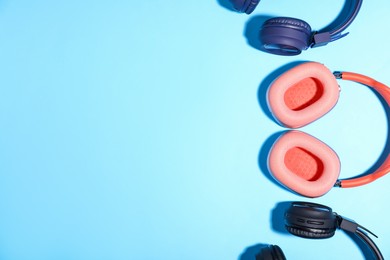 Photo of Different stylish headphones on light blue background, flat lay. Space for text