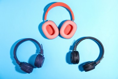 Photo of Different stylish headphones on light blue background, flat lay