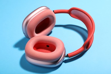 Photo of Pair of stylish pink headphones on light blue background