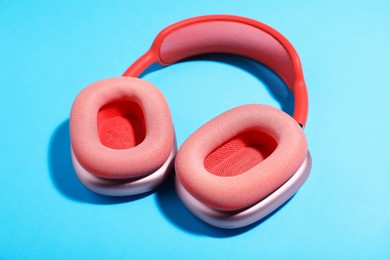 Photo of Pair of stylish pink headphones on light blue background