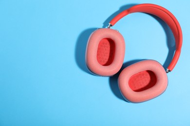 Photo of Pair of stylish pink headphones on light blue background, top view. Space for text