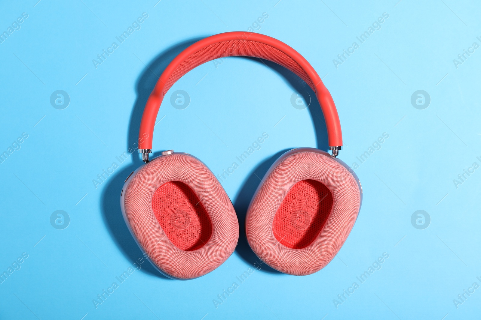 Pair of stylish pink headphones on light blue background, top view Photo of Pair of stylish pink headphones on light blue background, top view