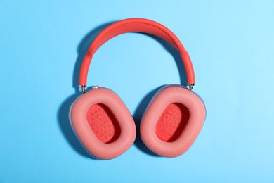 Photo of Pair of stylish pink headphones on light blue background, top view