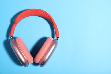 Photo of Pair of stylish pink headphones on light blue background, top view. Space for text