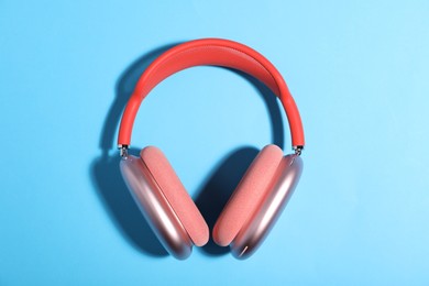 Photo of Pair of stylish pink headphones on light blue background, top view