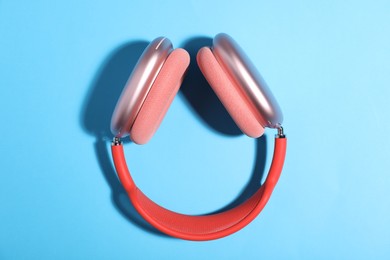 Photo of Pair of stylish pink headphones on light blue background, top view