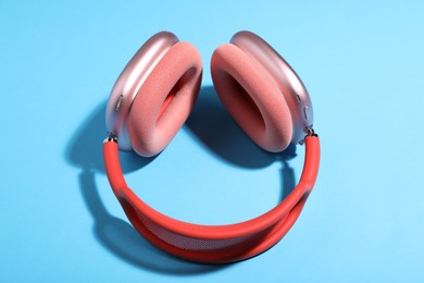 Photo of Pair of stylish pink headphones on light blue background, above view