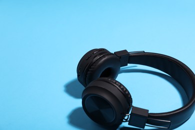 Photo of Pair of stylish headphones on light blue background, closeup. Space for text