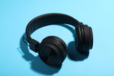 Photo of Pair of stylish headphones on light blue background, closeup