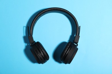 Photo of Pair of stylish headphones on light blue background, top view