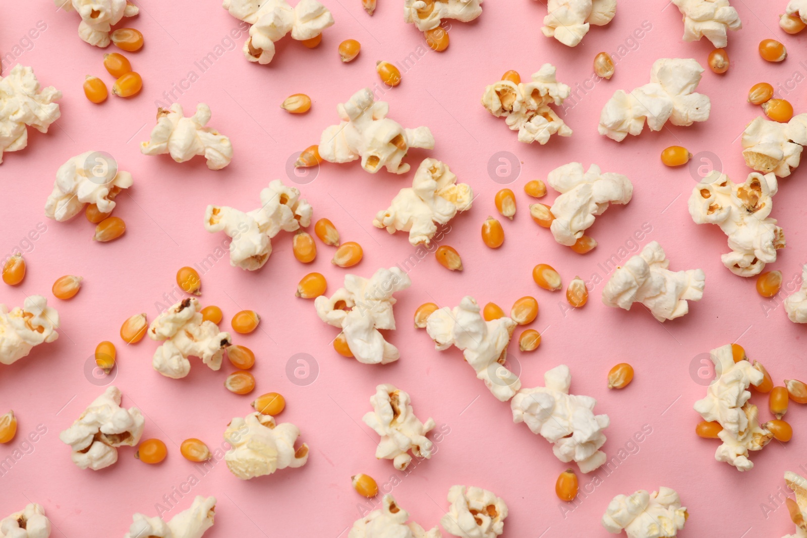Tasty popcorn and dry kernels on pink background, flat lay Photo of Tasty popcorn and dry kernels on pink background, flat lay