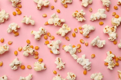 Photo of Tasty popcorn and dry kernels on pink background, flat lay