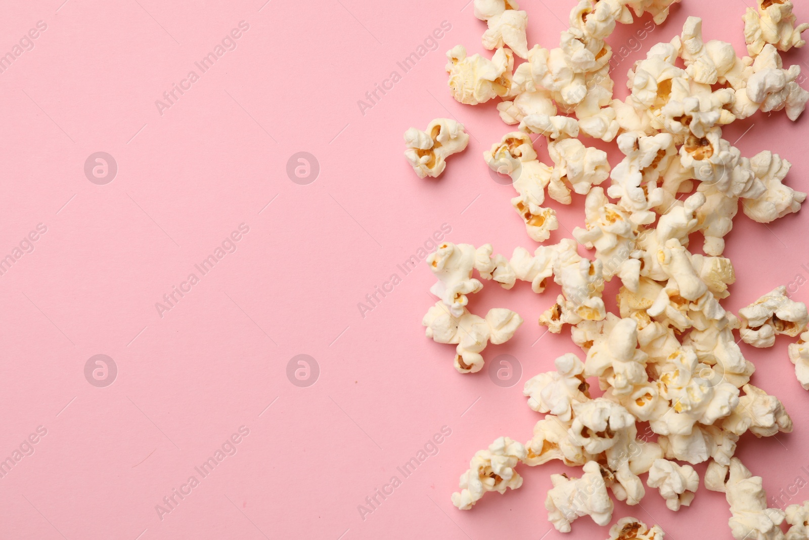 Photo of Tasty popcorn on pink background, flat lay. Space for text