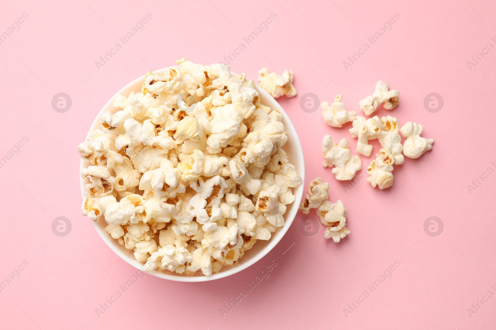 Tasty popcorn in bowl on pink background, flat lay Photo of Tasty popcorn in bowl on pink background, flat lay