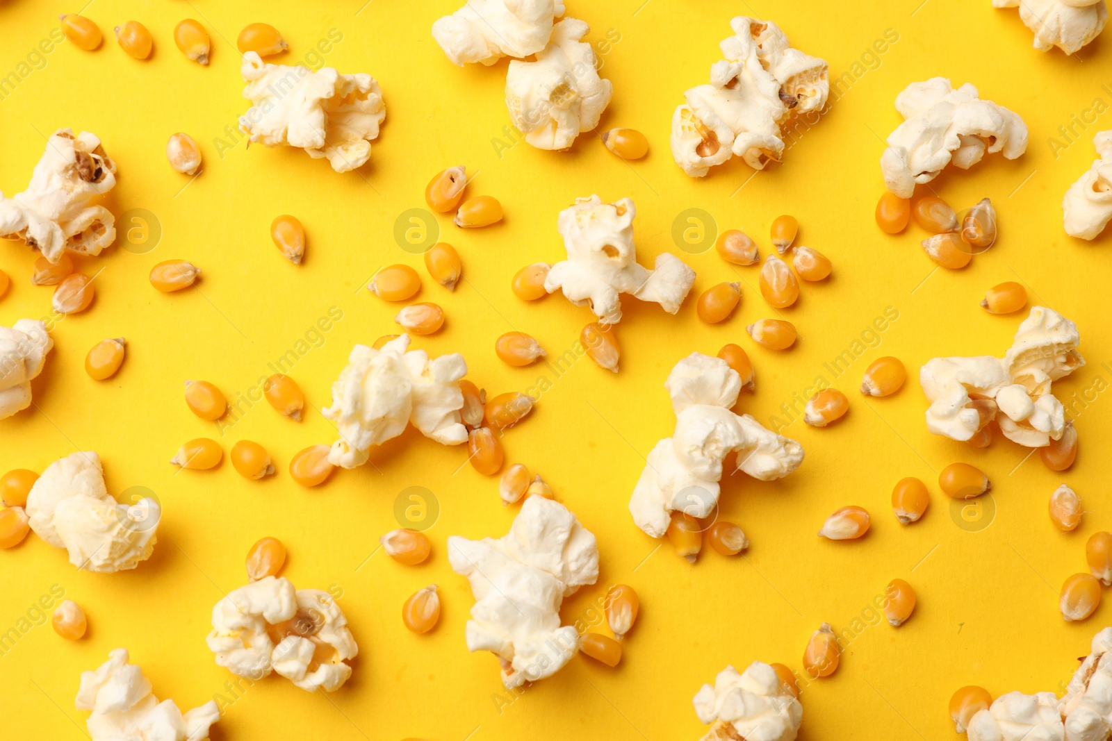 Tasty popcorn and dry kernels on yellow background, flat lay Photo of Tasty popcorn and dry kernels on yellow background, flat lay