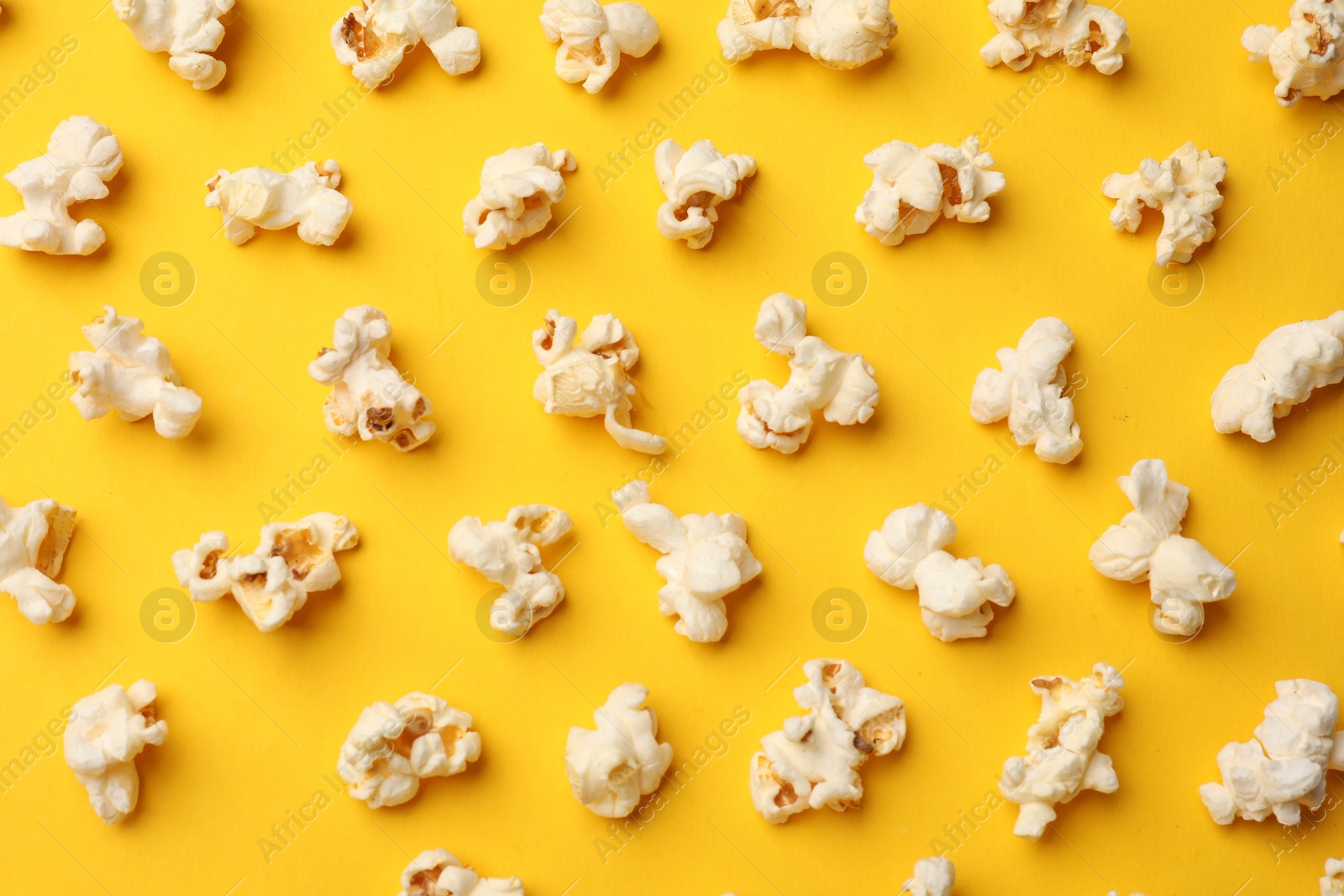 Photo of Tasty popcorn on yellow background, flat lay