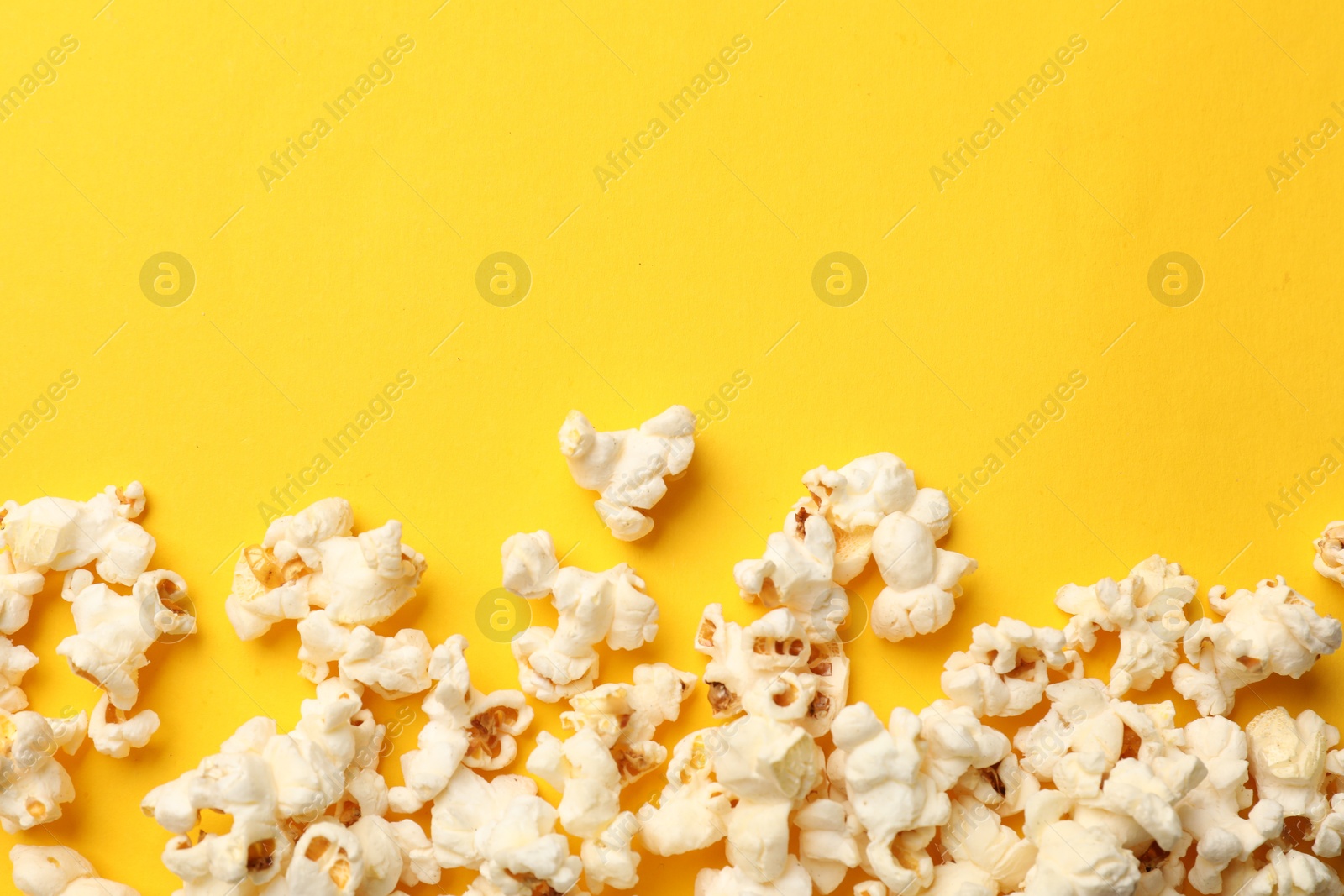 Tasty popcorn on yellow background, flat lay. Space for text Photo of Tasty popcorn on yellow background, flat lay. Space for text
