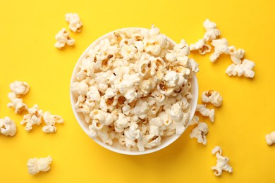 Photo of Tasty popcorn in bowl on yellow background, flat lay