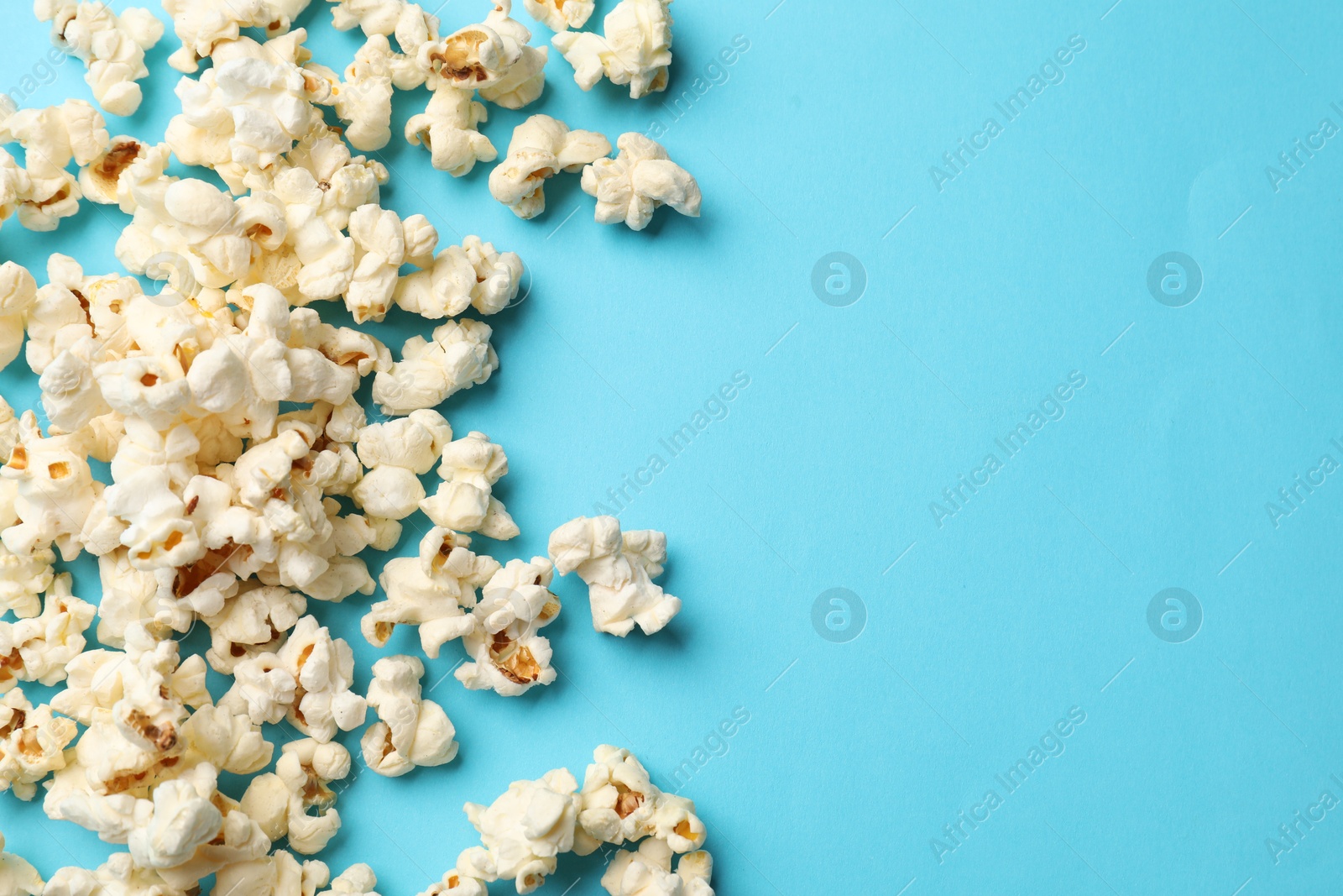 Tasty popcorn on light blue background, flat lay. Space for text Photo of Tasty popcorn on light blue background, flat lay. Space for text