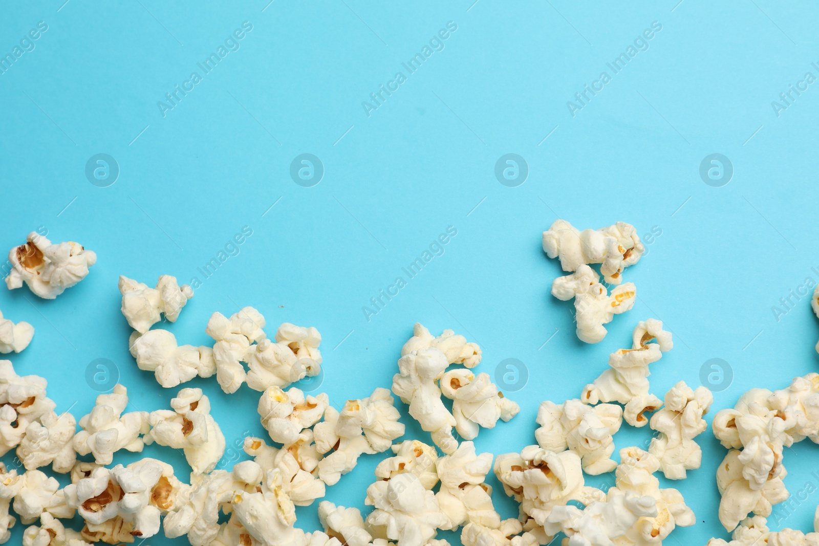 Tasty popcorn on light blue background, flat lay. Space for text Photo of Tasty popcorn on light blue background, flat lay. Space for text