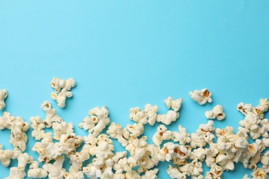 Photo of Tasty popcorn on light blue background, flat lay. Space for text
