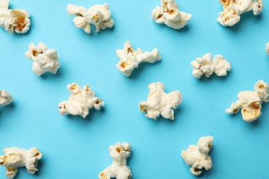 Photo of Tasty popcorn on light blue background, flat lay