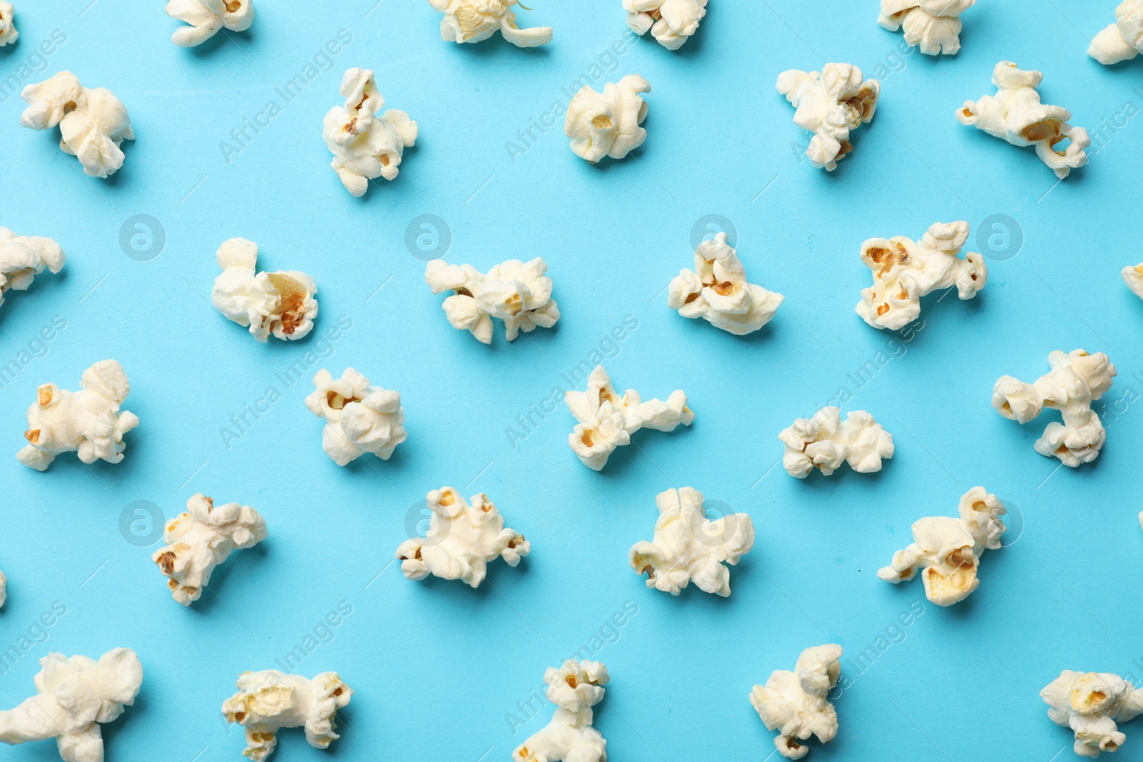 Photo of Tasty popcorn on light blue background, flat lay
